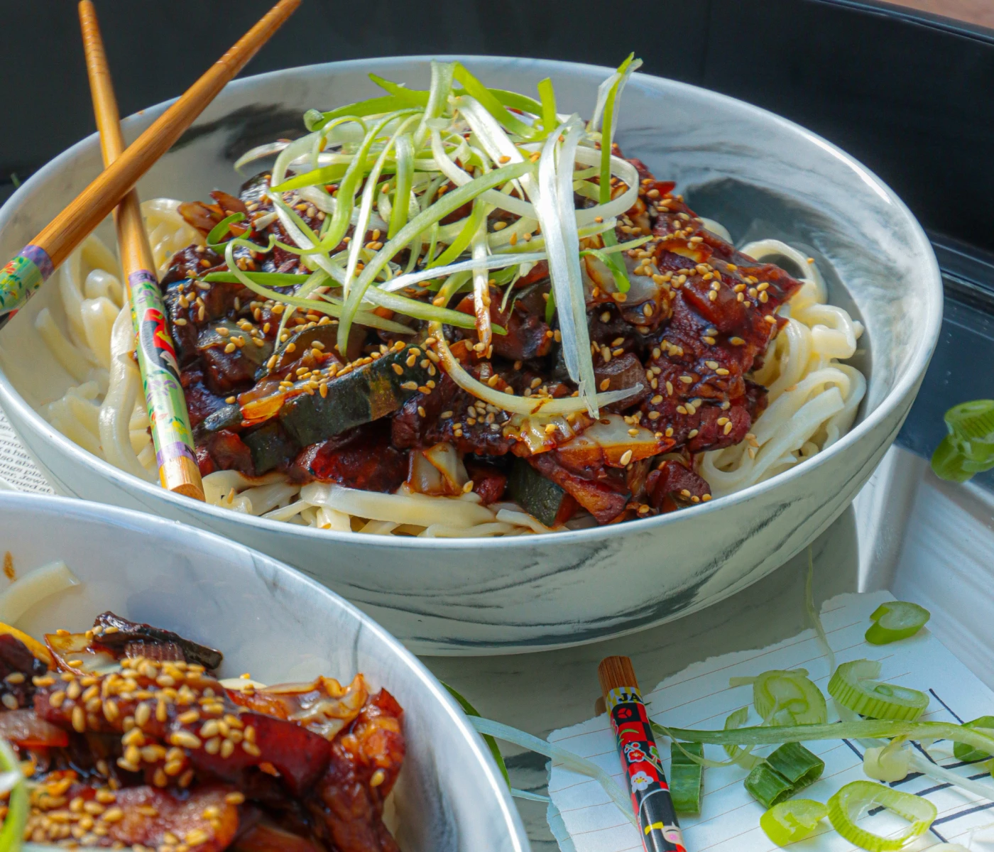 Black bean noodles topped with green onions.