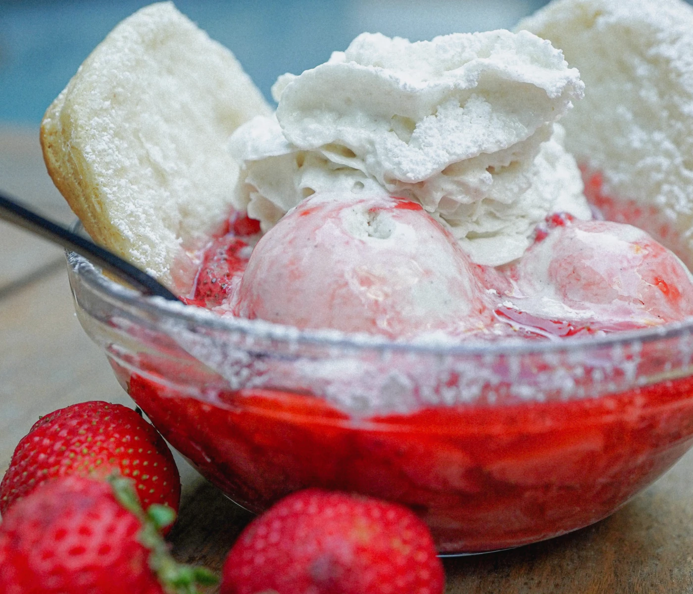 Mini strawberry shortcakes in a bowl with ice cream and whipped cream.