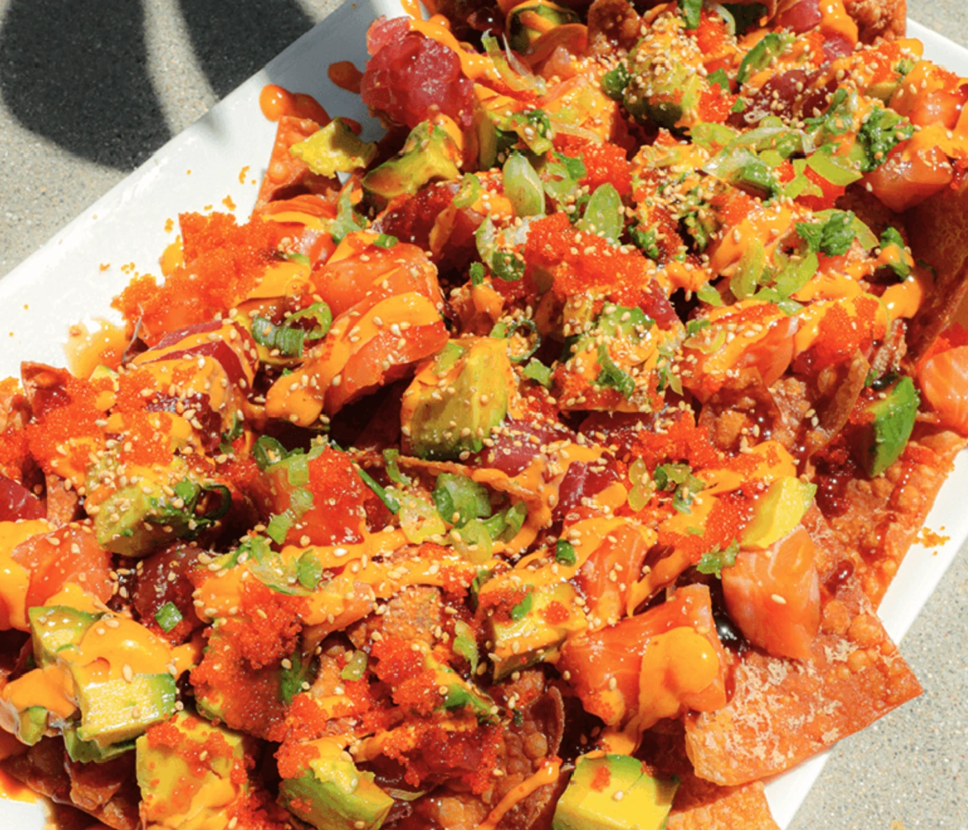 Nachos topped with raw tuna and salmon and avocado.