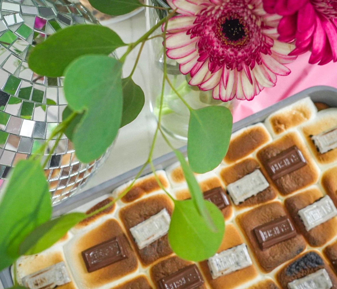 Backdrop of s'mores cookie bars with a disco bar and flowers in the foreground.