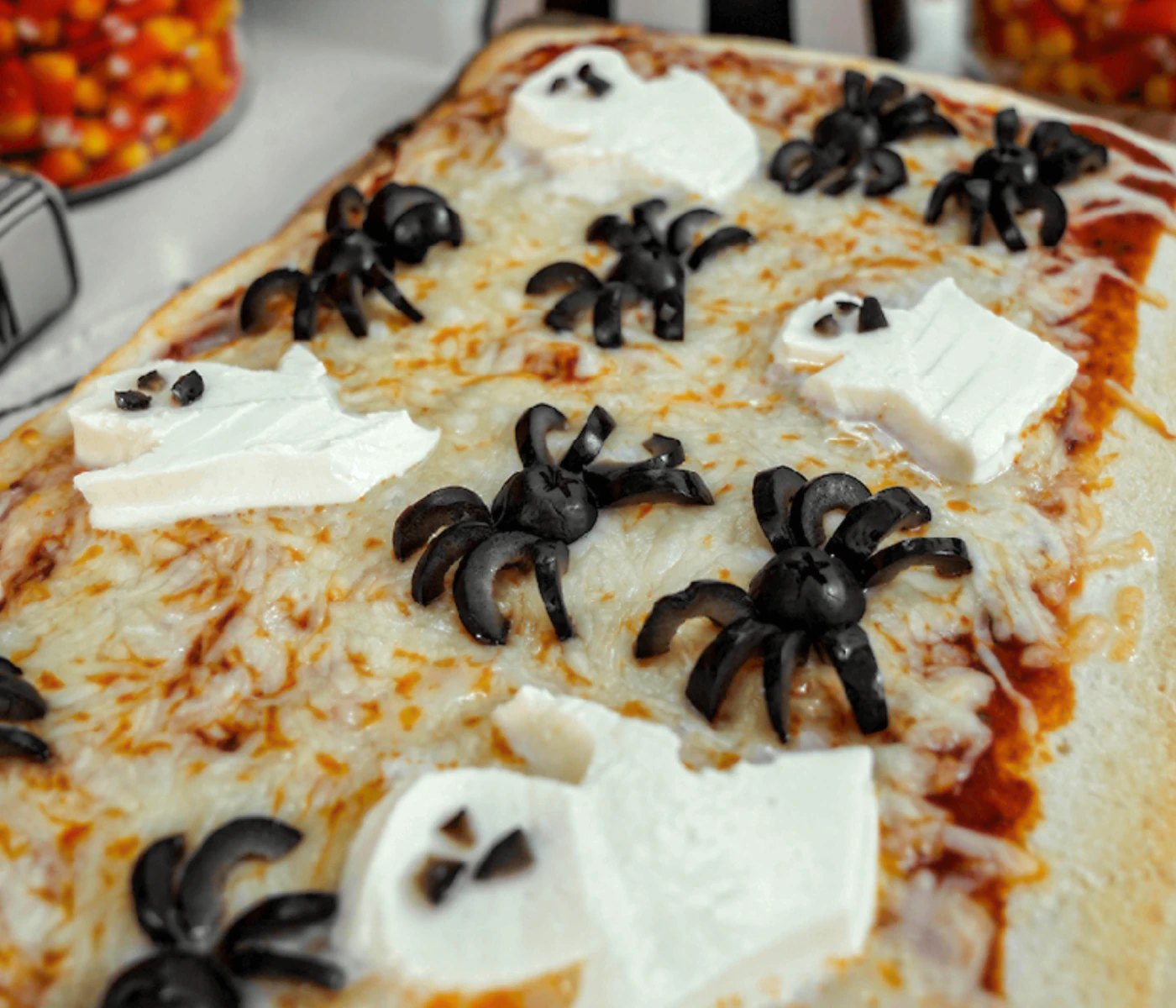 Cheese pizza with mozzarella ghosts and black olive spiders.