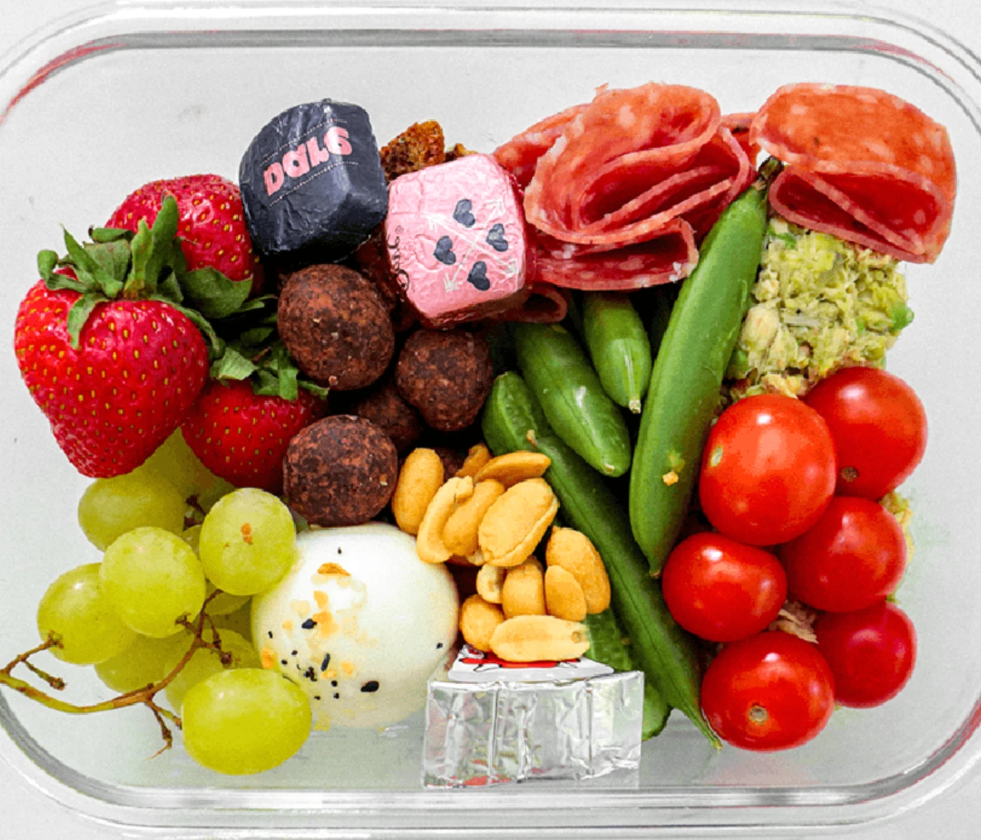 Snack box with tuna salad, veggies, fruit, nuts, cheese and chocolate.